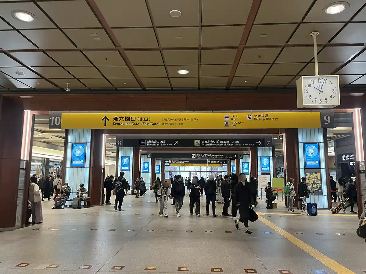 Kanazawa Station central concourse with Shinkansen and Kenrokuen Gate signs for passengers.