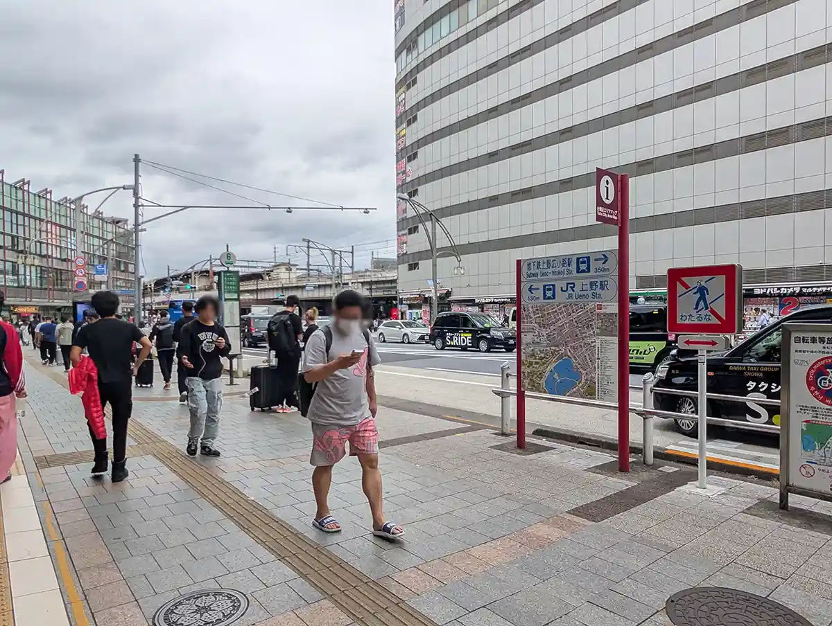 Street-level exit area near Keisei Ueno Station with a map and signs to JR Ueno