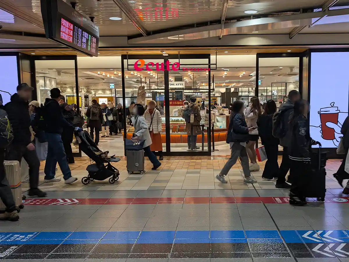 Entrance to ecute Shinagawa shopping area inside Shinagawa Station with food shops and travelers passing