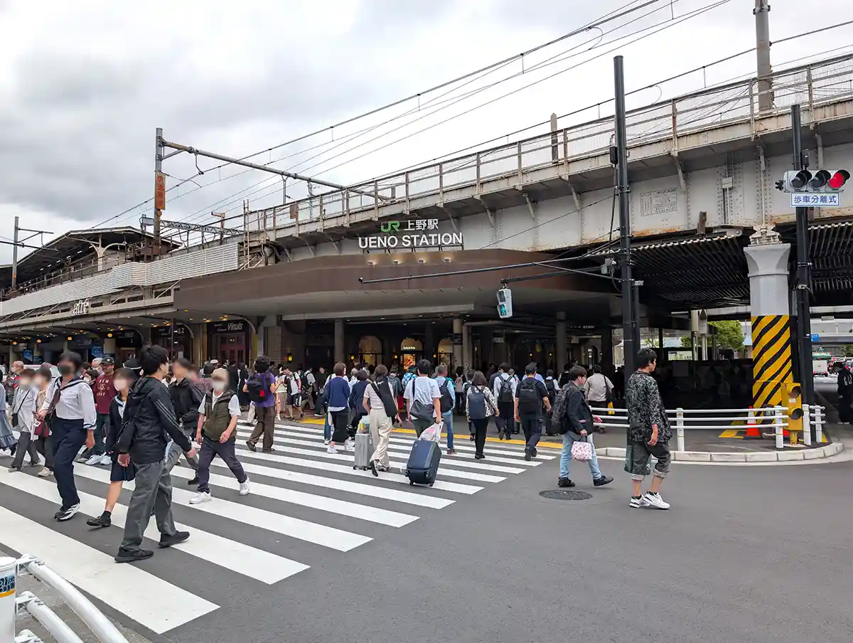 Street crossing in front of JR Ueno Station with people walking toward the station building