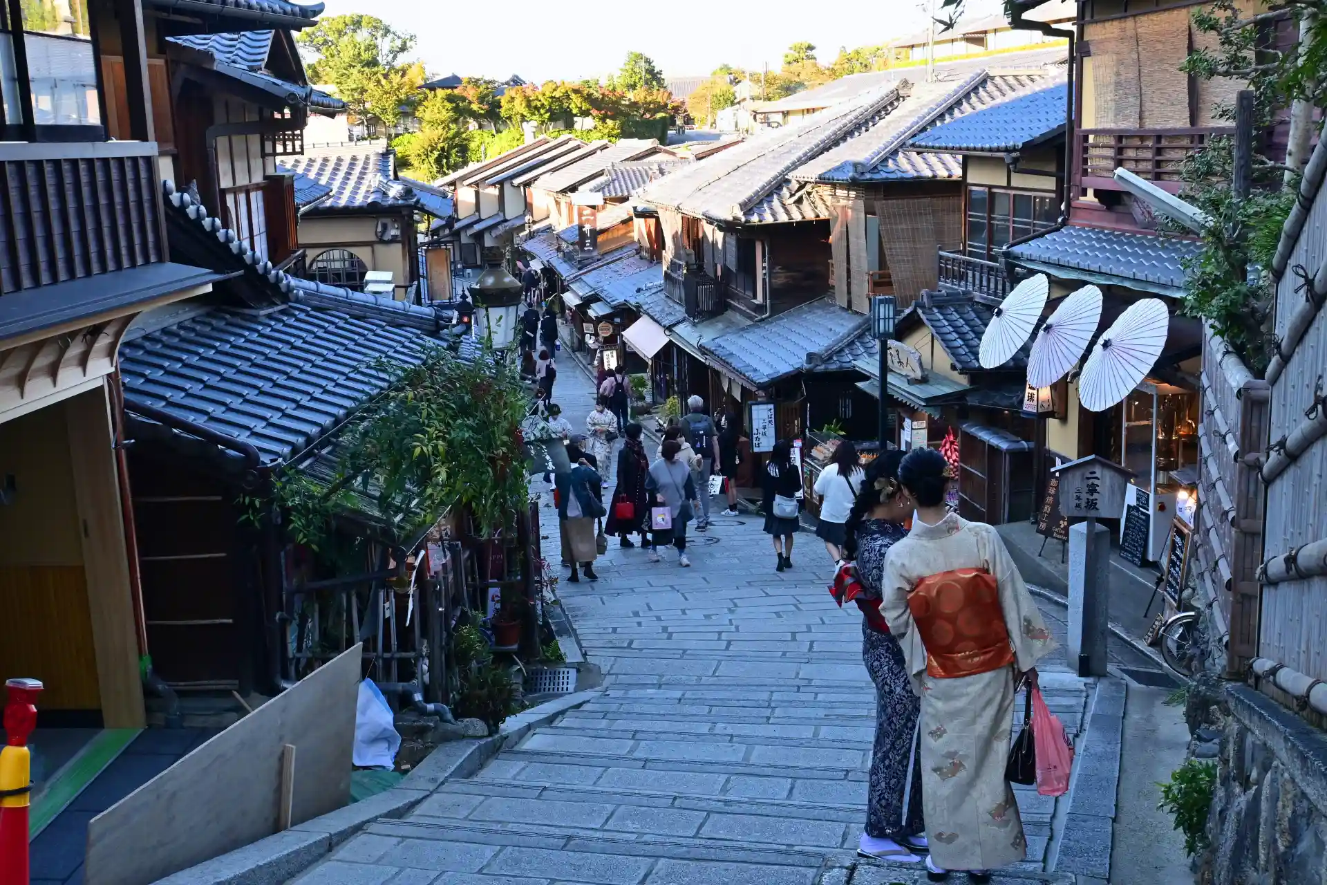 Visitors walking along Ninenzaka in Kyoto with old wooden buildings and tiled roofs
