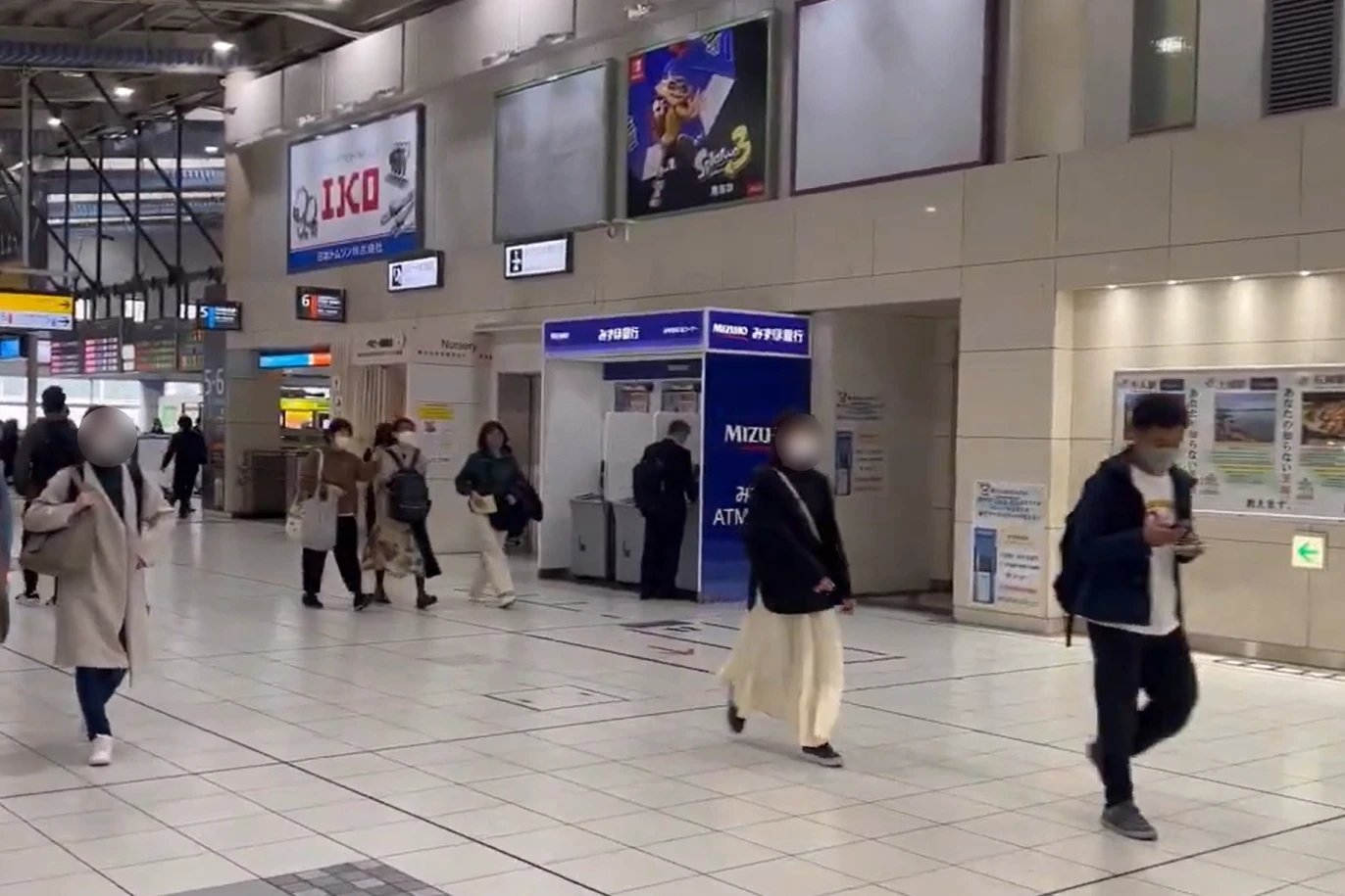 Mizuho Bank ATM inside Shinagawa Station with travelers passing by