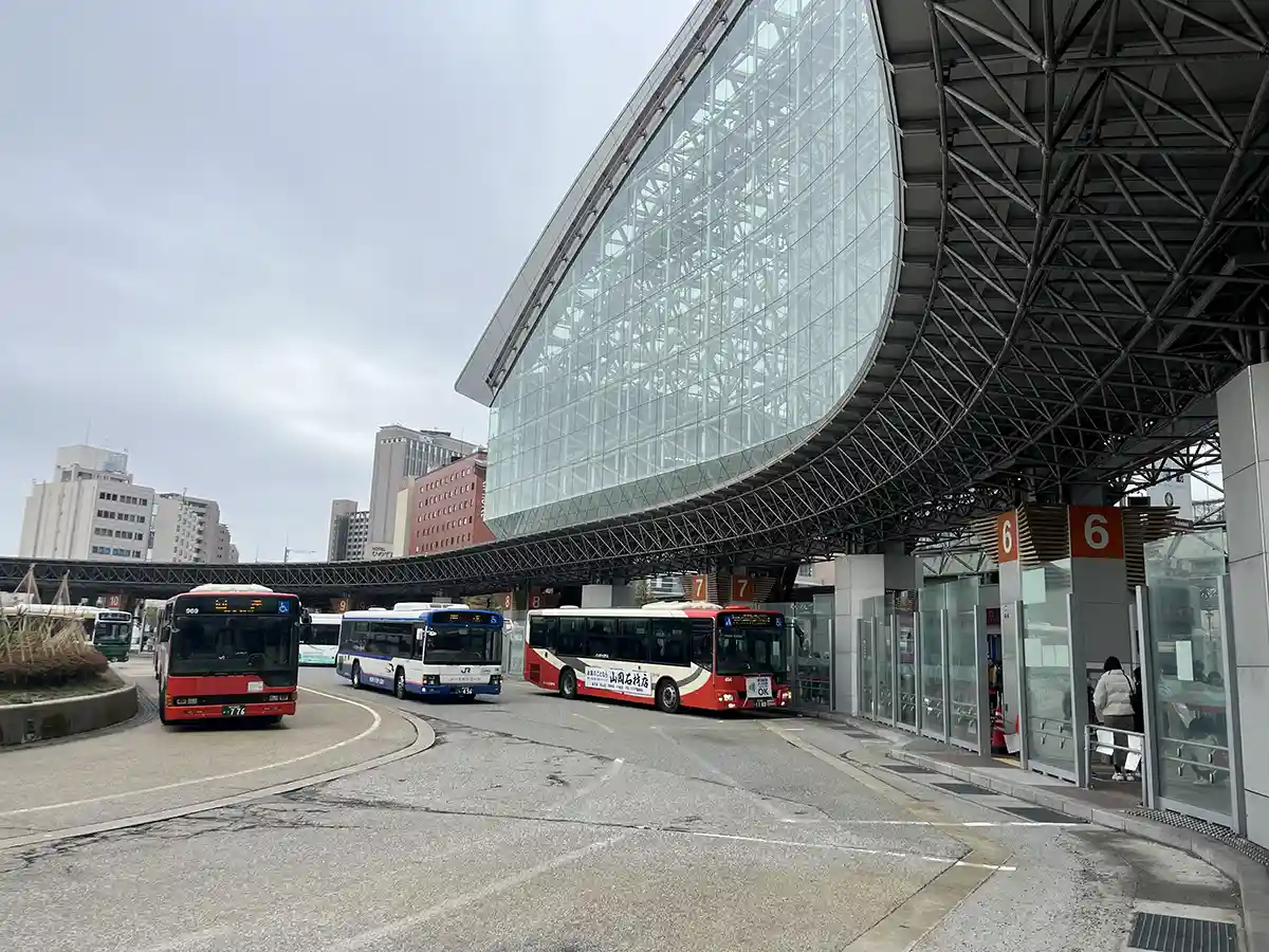 Bus terminal outside Kanazawa Station with city buses at boarding stops for local travel.