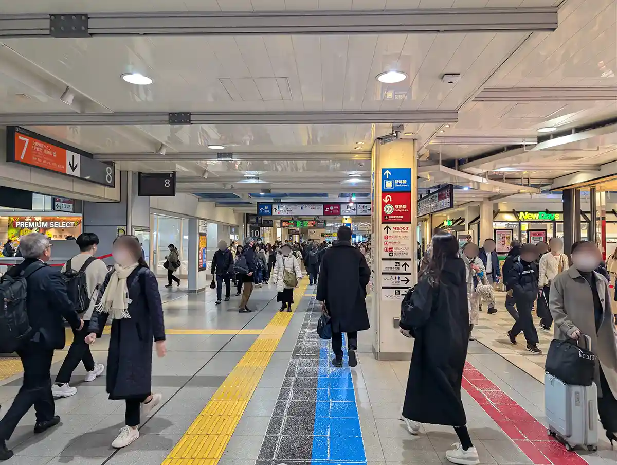 JR concourse at Shinagawa Station with passengers walking past local train platforms toward Shinkansen area
