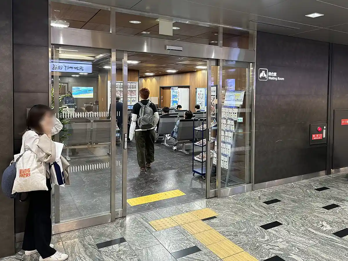 Waiting room inside the Shinkansen ticket gate area at Hakata Station with seated passengers