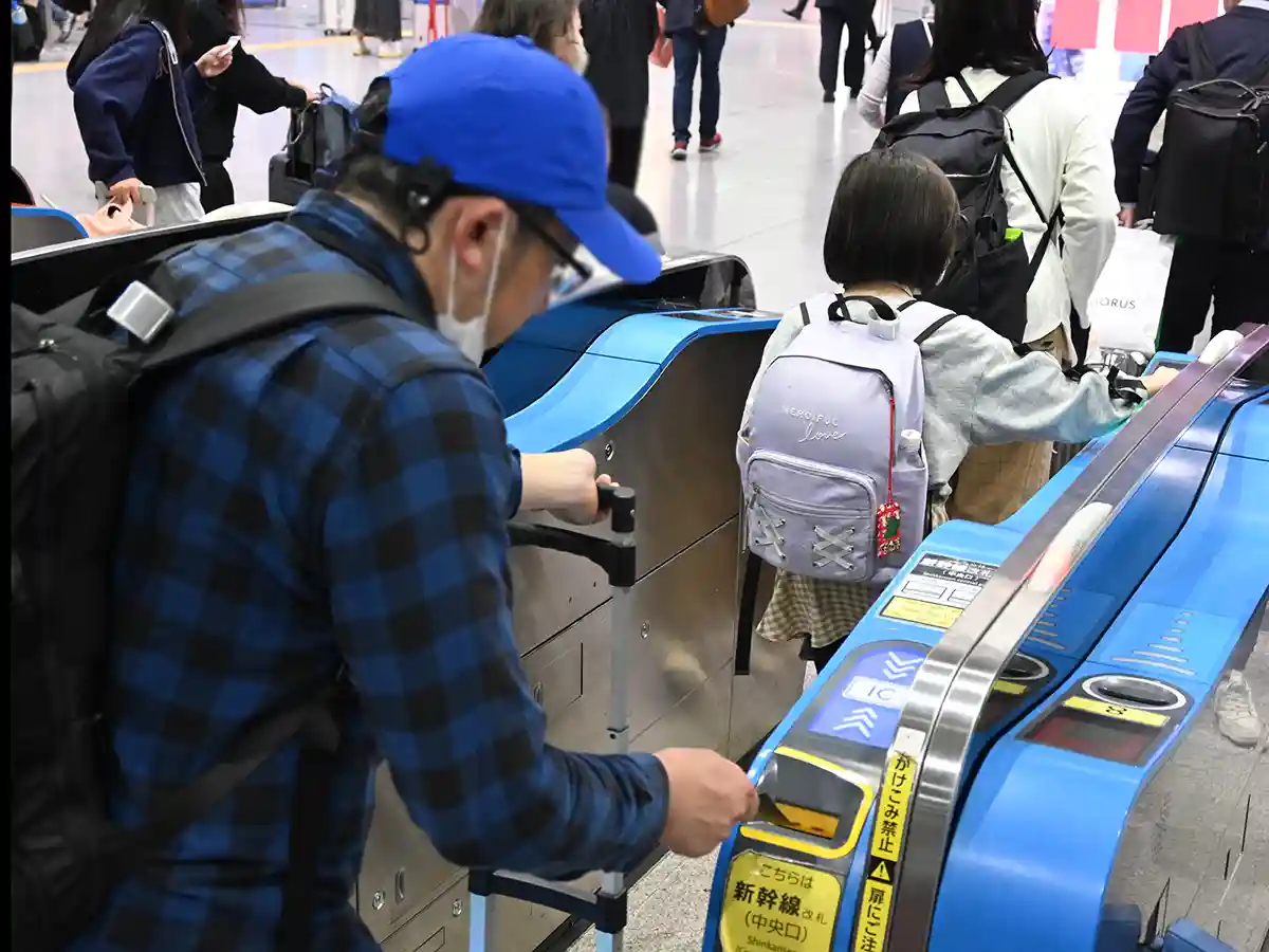 Passengers passing through Shinkansen ticket gates at Shin-Osaka Station with luggage and tickets