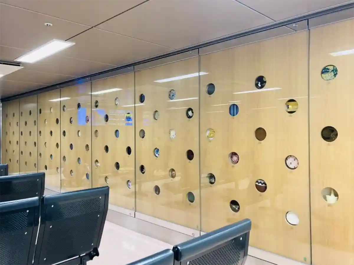 Hyakkou waiting room inside Kanazawa Station Shinkansen gates with traditional crafts in glass wall.