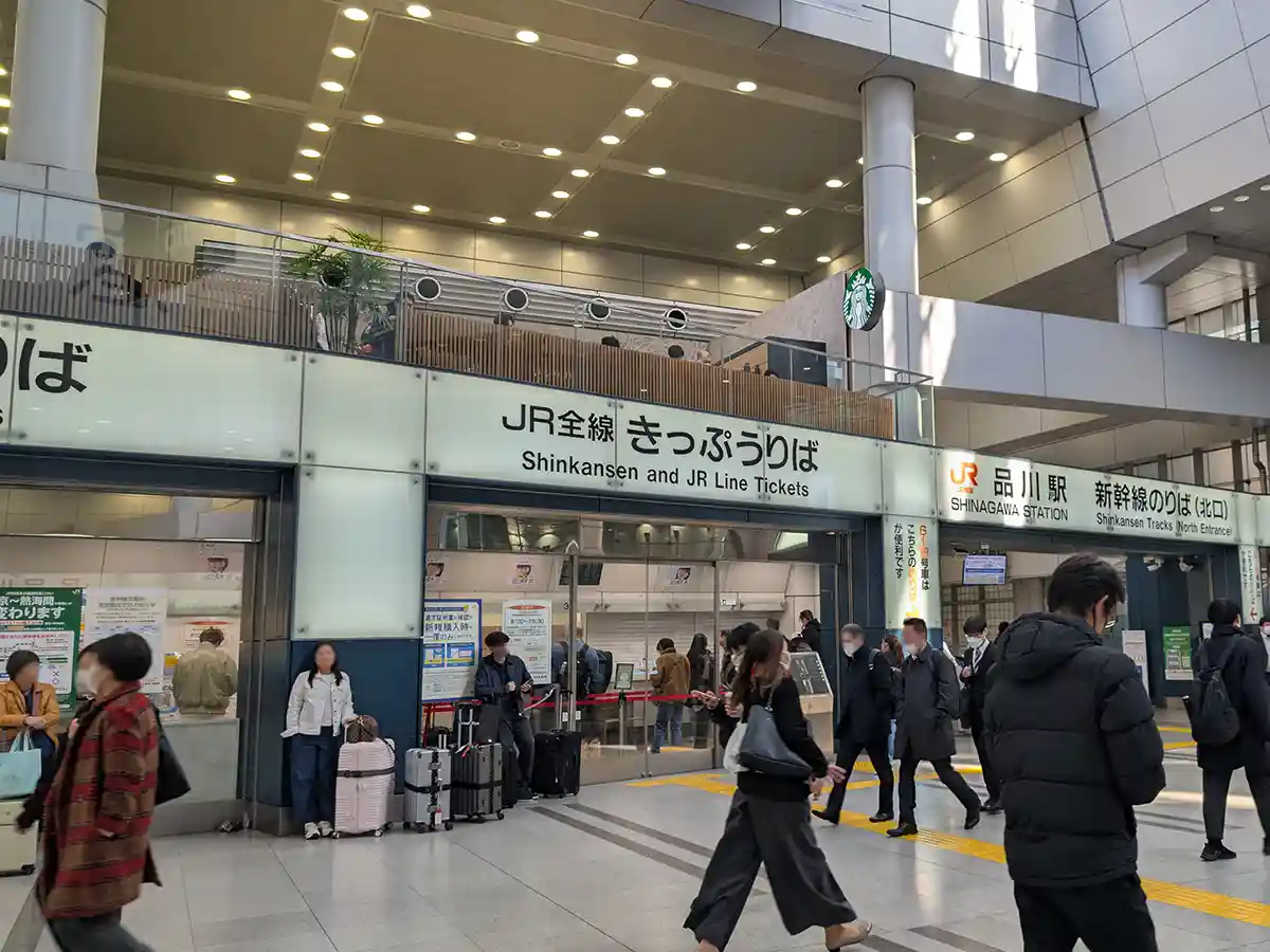 Shinkansen and JR ticket office at Shinagawa Station with travelers waiting at the ticket counters