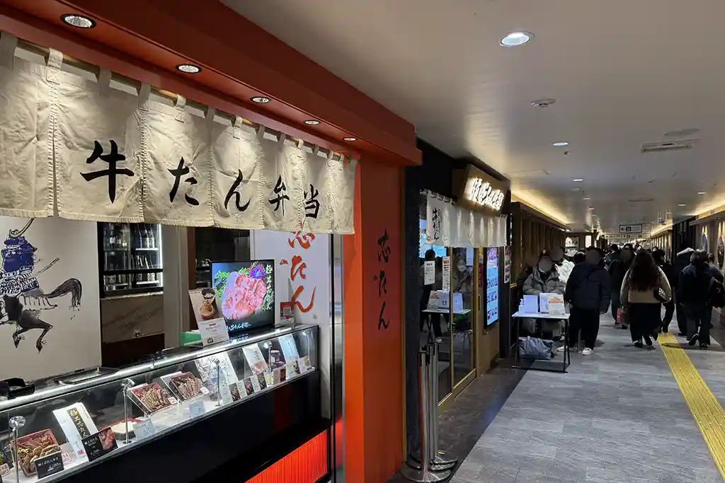 Indoor walkway at Sendai Station Gyutan Street lined with beef tongue restaurants and passengers moving through the area.