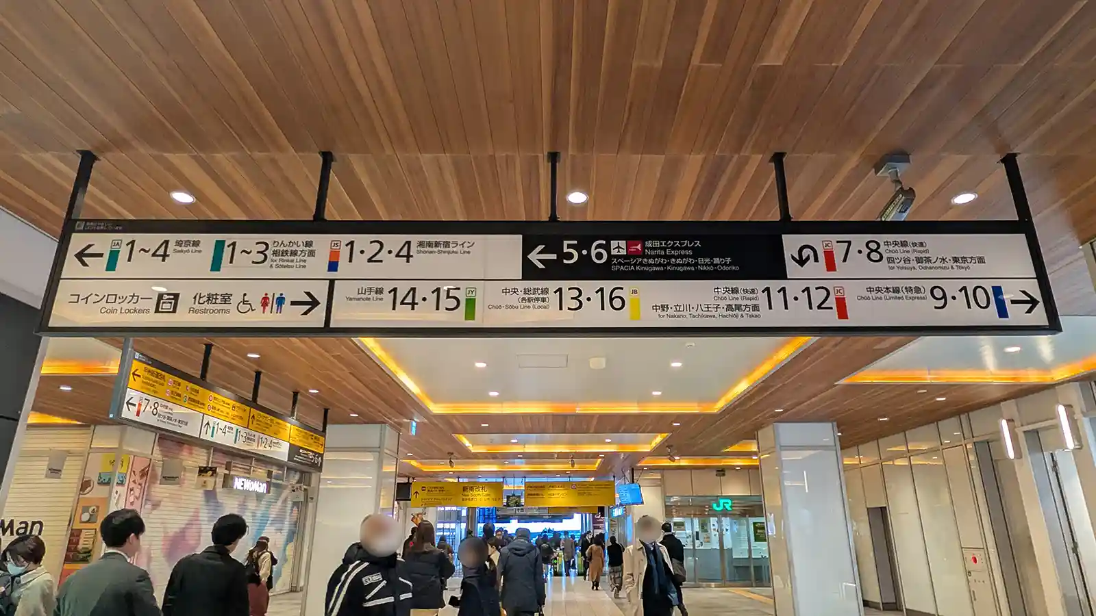 Platform direction signs inside Shinjuku Station showing routes for Narita express and other JR lines