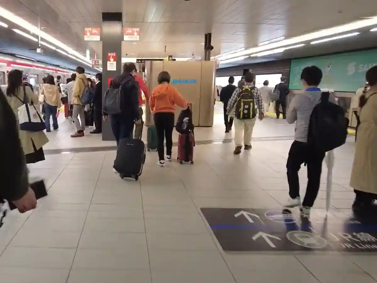 Passengers walking on Midosuji Line platform at Shin-Osaka Station heading toward Shinkansen transfer area