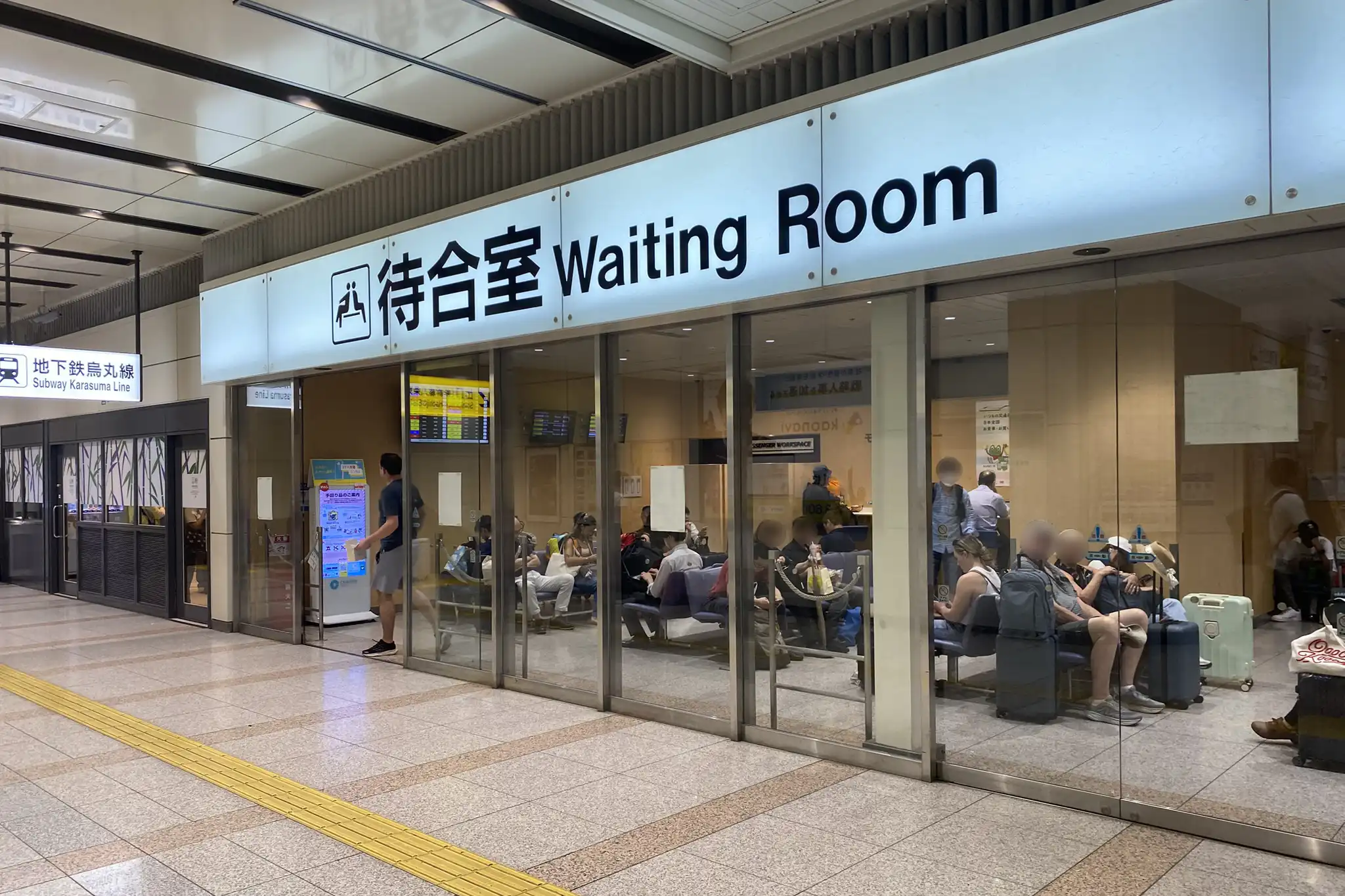 Shinkansen waiting room at Kyoto Station with passengers seated inside, providing a quiet space before boarding