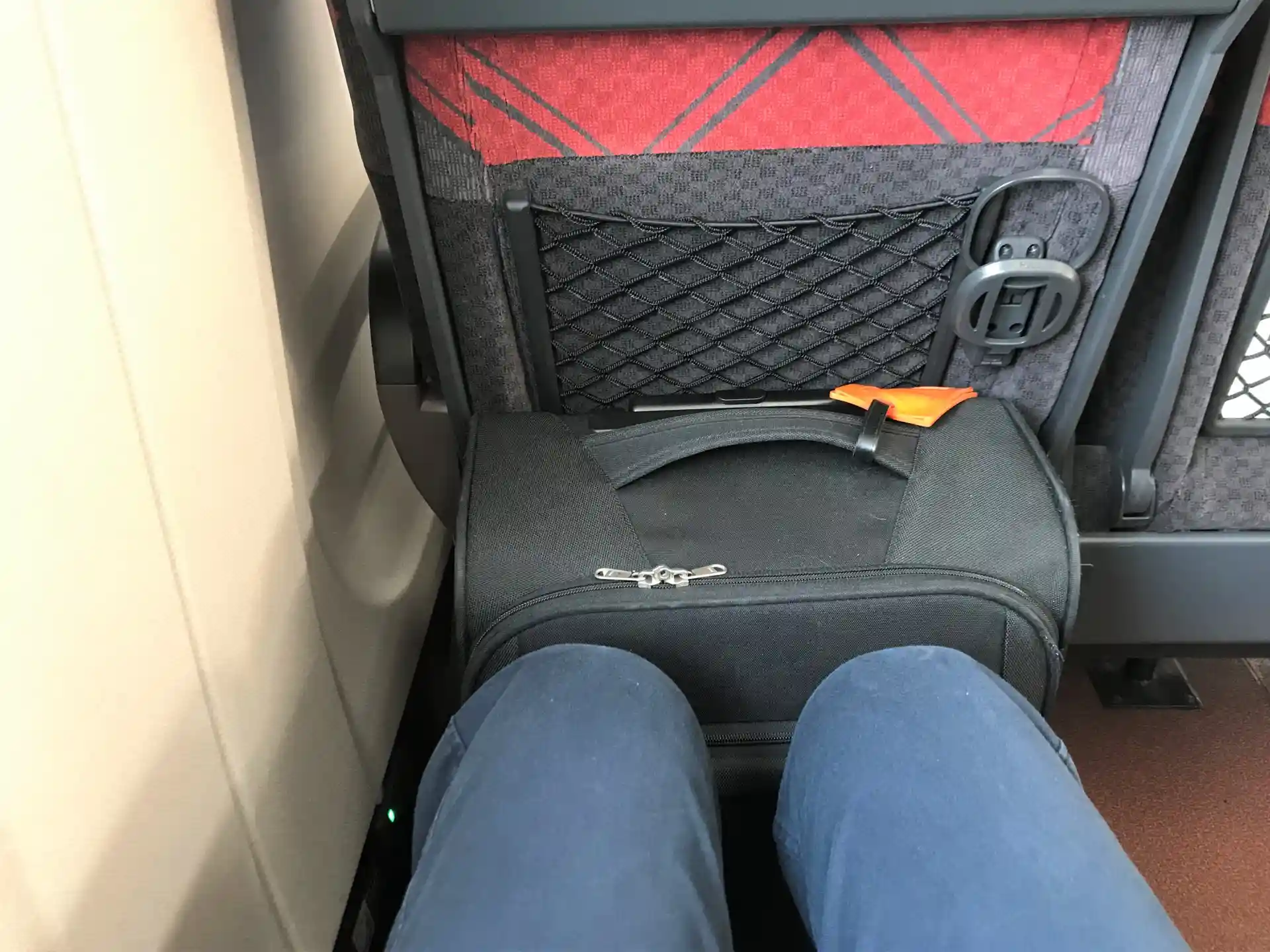 Shinkansen seat legroom area with a small suitcase placed on the floor in front of the seat.