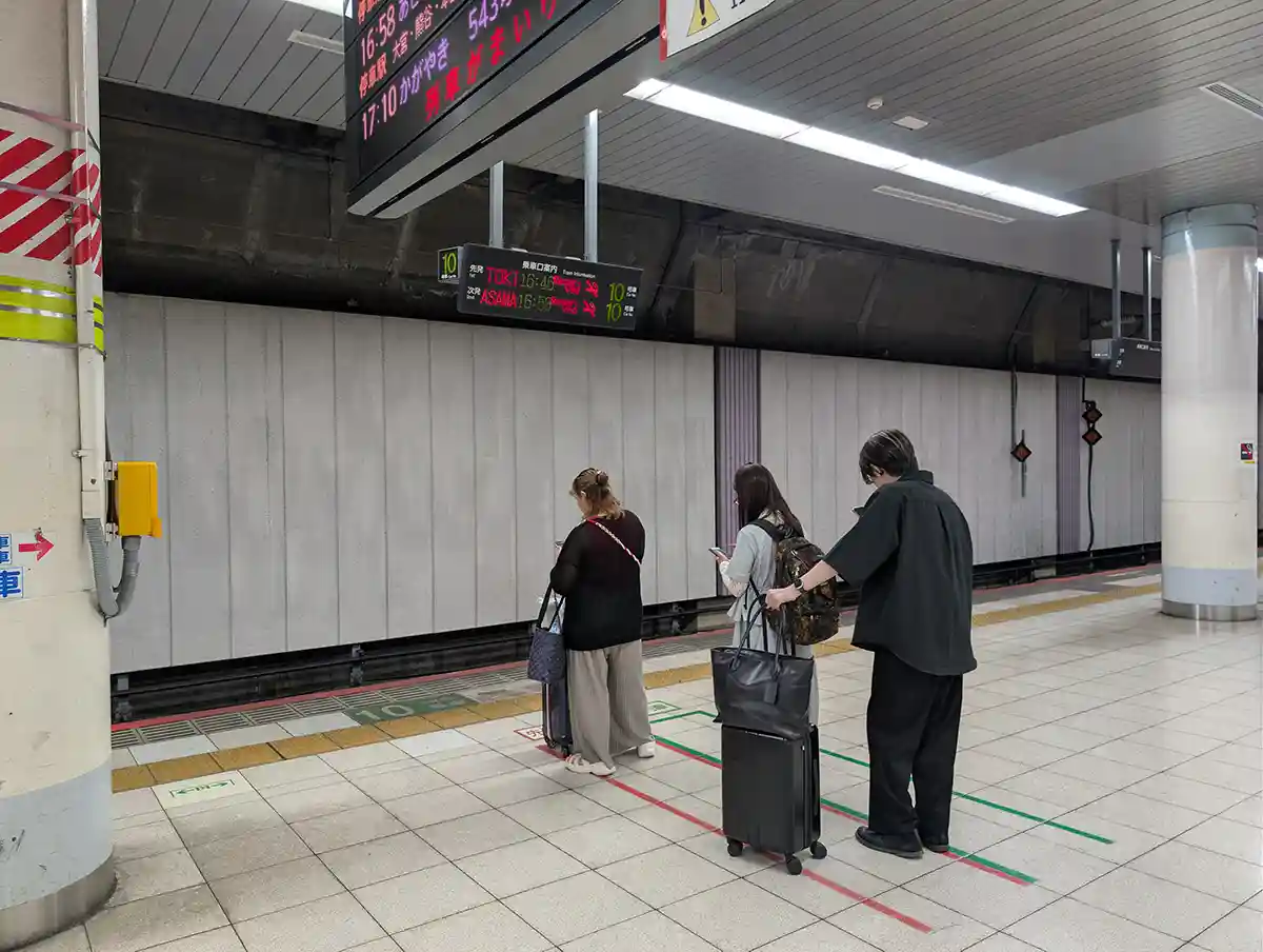 Passengers waiting in line on the JR Ueno Station Shinkansen platform with luggage