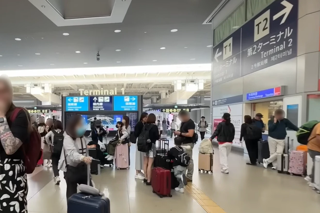 Travelers near signs for Terminal 1 and Terminal 2 at Kansai International Airport