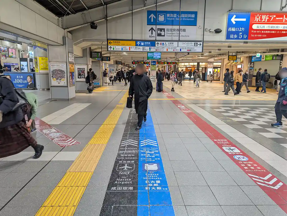Floor markings and overhead signs in Shinagawa Station JR concourse guiding passengers to Shinkansen platforms