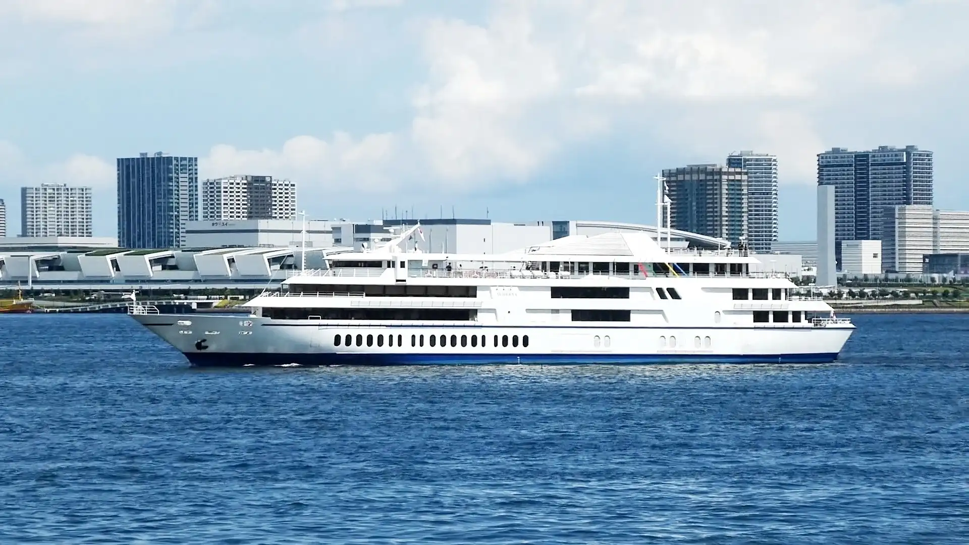 Tokyo Bay Symphony cruise ship passing high-rise buildings near the waterfront
