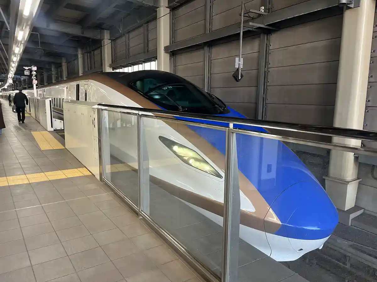 Hokuriku Shinkansen train stopped at Kanazawa Station platform with safety barriers.