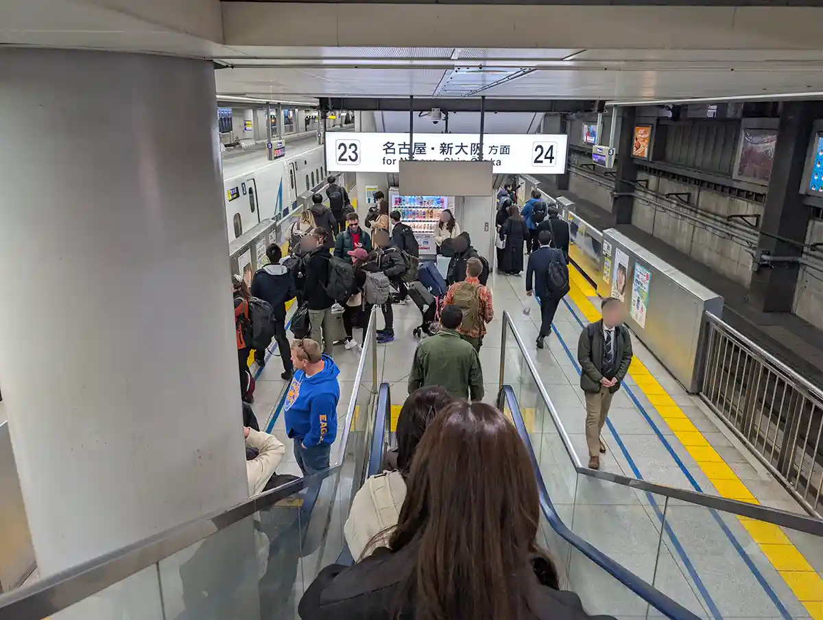 Escalator descending to Shinkansen platforms at Shinagawa Station with passengers heading to tracks 23 and 24