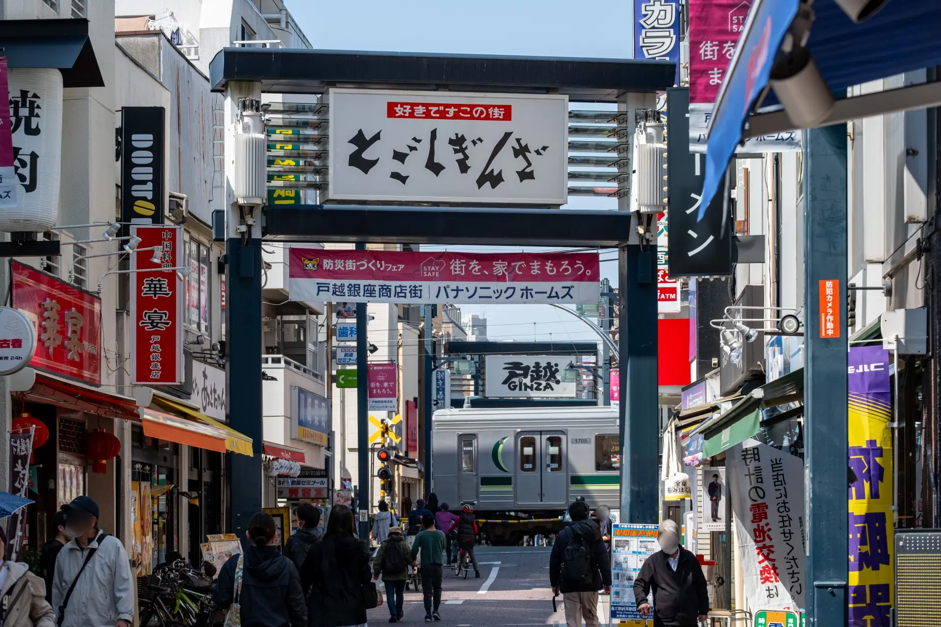 Street view of Togoshi Ginza Shopping Street featuring local shops and a passing train