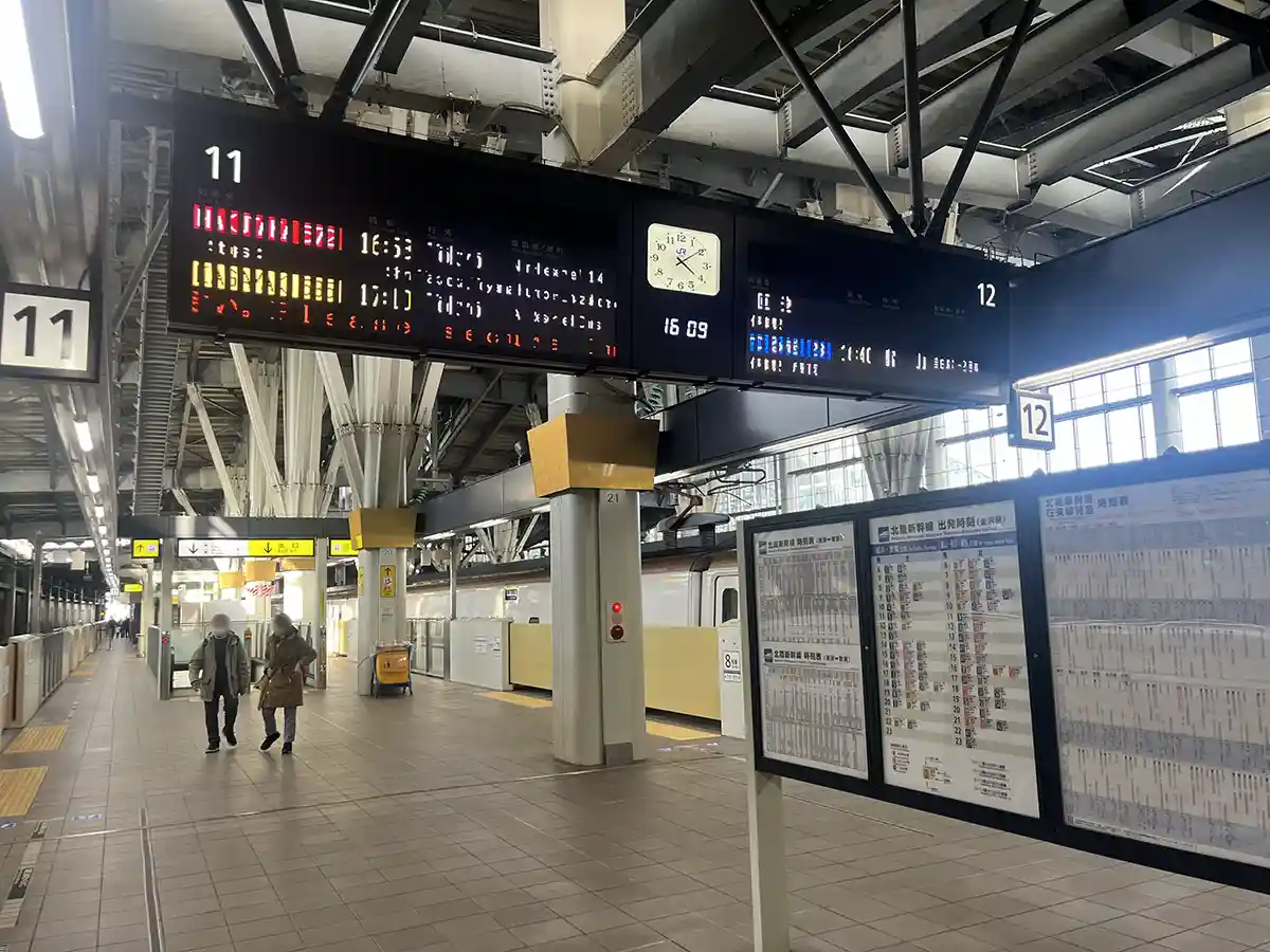 Shinkansen platform 11 and 12 at Kanazawa Station with departure board and train tracks.