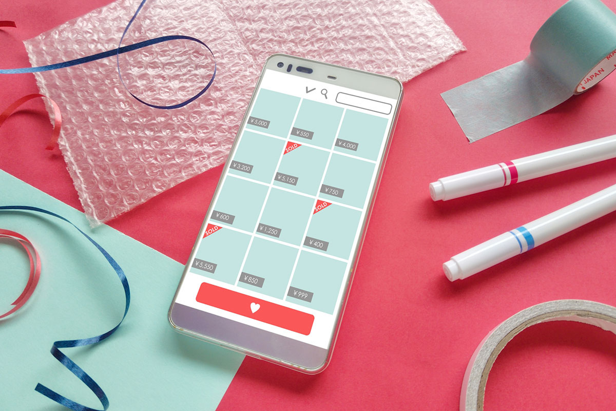 フリマアプリの画面が表示されたスマートフォンや梱包材料が並んでいる。