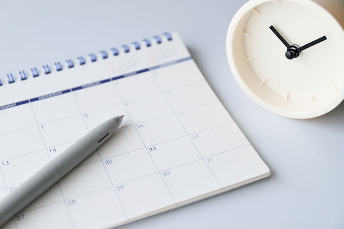 ボールペンとカレンダー、時計が置かれている。
