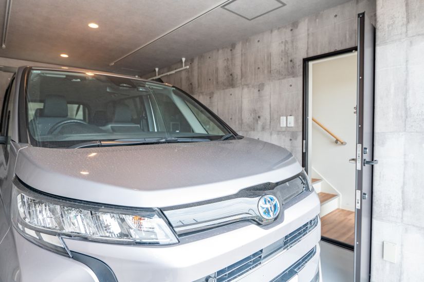 ガレージに車を入庫した状態の玄関とガレージをつなぐ扉の画像。車をガレージに入庫した状態でも、十分にガレージへの扉を開閉できるスペースがある。