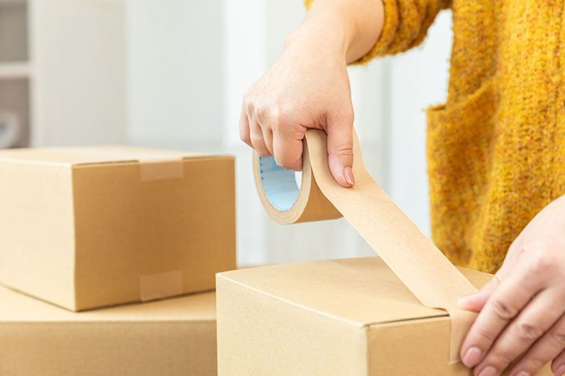 段ボールの梱包作業をする女性の手元。