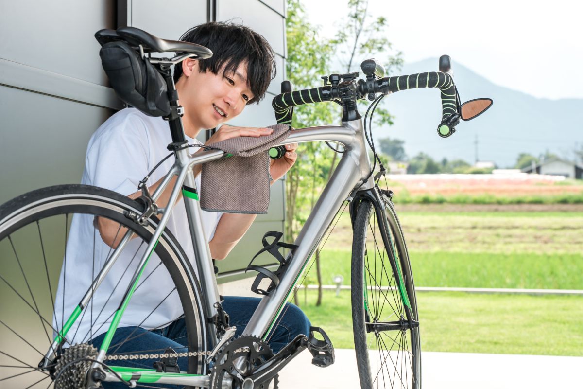自転車を布で拭く男性。