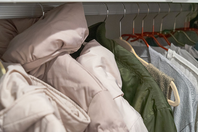 クローゼットに冬物のダウンやジャケットが掛かっている写真