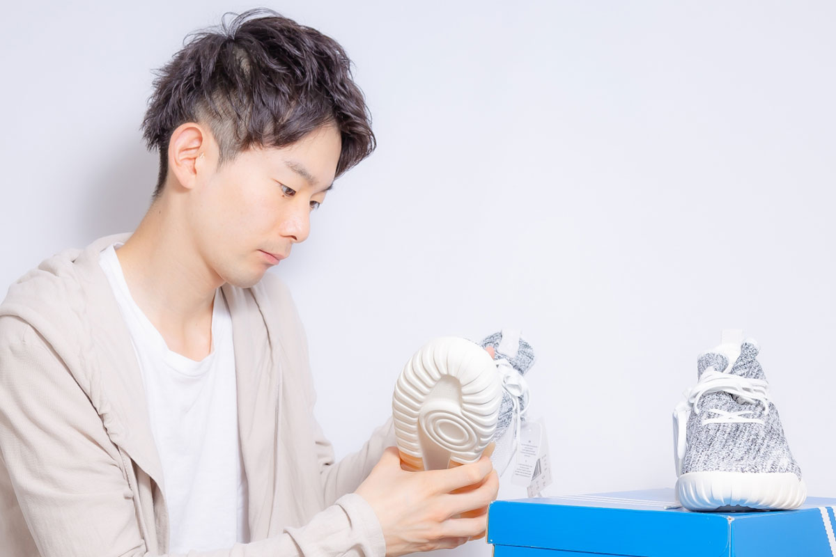 箱からスニーカーを取り出している人物。