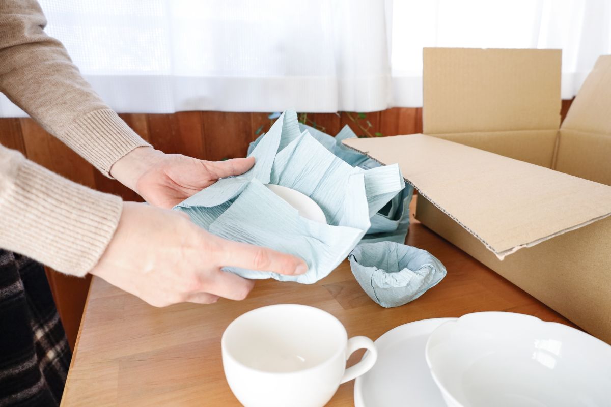 食器を緩衝材で包んで段ボールに梱包する作業