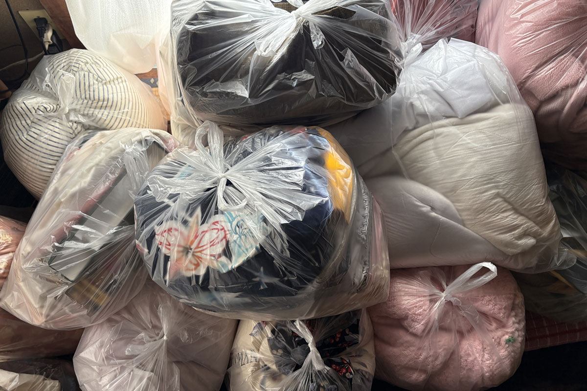 衣類などの布類が入ったゴミ袋が積み上げられている。