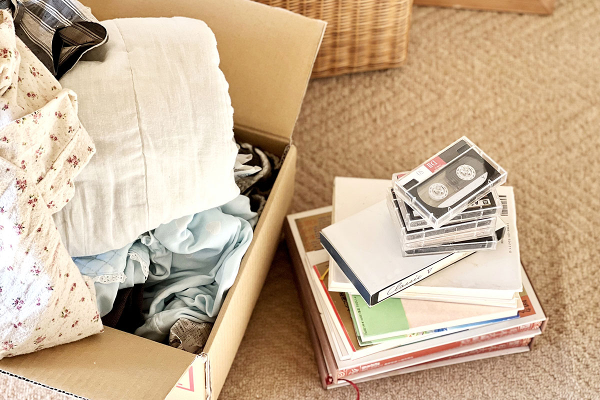 本の上に積み上げたビデオテープとカセットテープと段ボール箱。