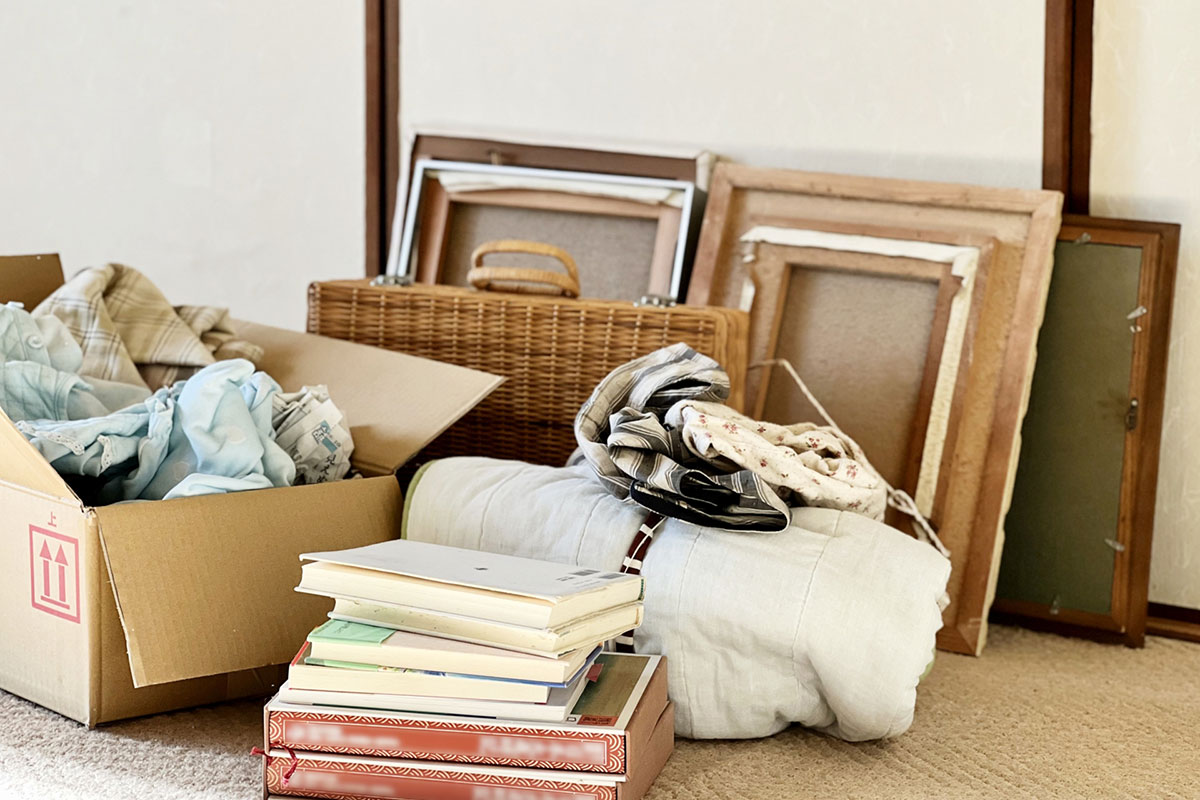 段ボール箱に入れた衣類と本といくつかの額縁。