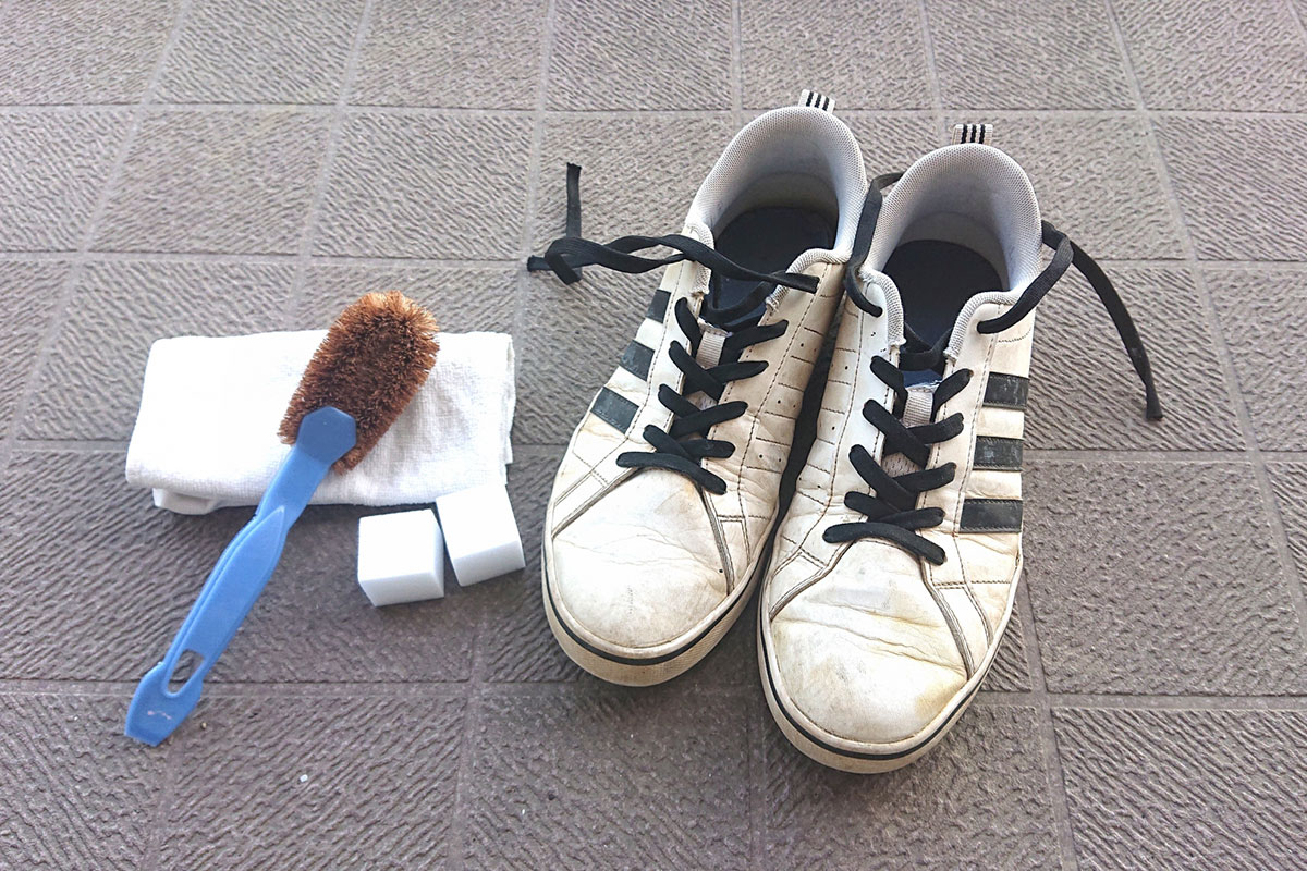 白黒のスニーカーとスポンジやブラシなどスニーカーを洗う道具。
