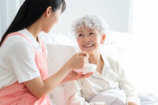 食事介助をする介護士と高齢者女性