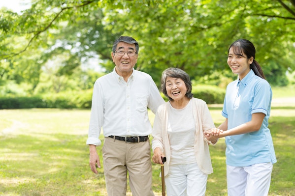 散歩する高齢者夫婦と介護士