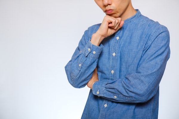 顎に手を当て首をかしげる男性