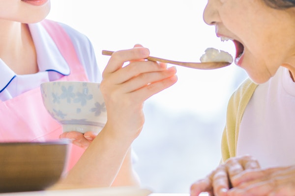 食事を口に運ばれている高齢者