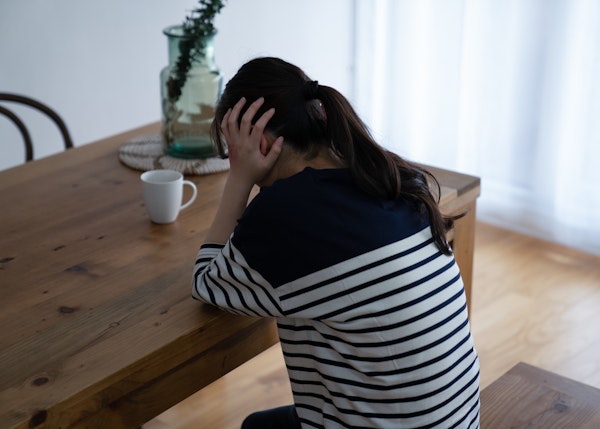 頭を抱える女性の後ろ姿