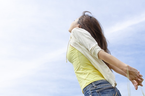 空を気持ちよさそうに見上げる女性