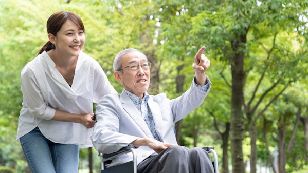 自然豊かな公園を散歩する車椅子の男性と娘