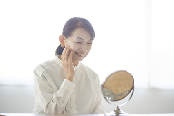 鏡を見てほほ笑む女性