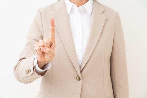 人差し指を立てるスーツを着た女性