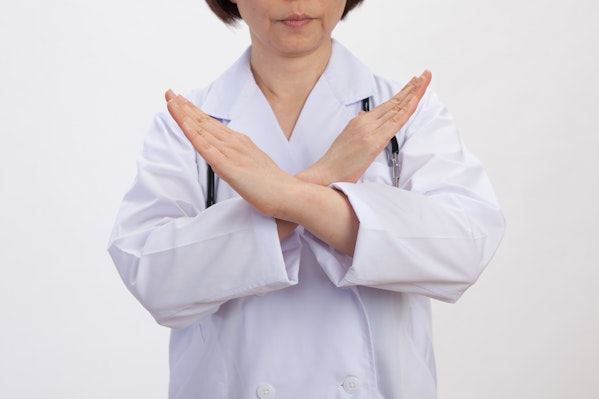 腕をバツにする白衣の女性