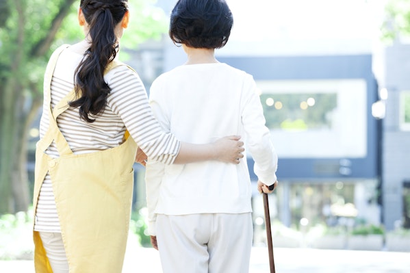 母の腰を支えて歩く娘