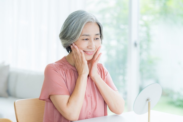 鏡の前でスキンケアをする女性