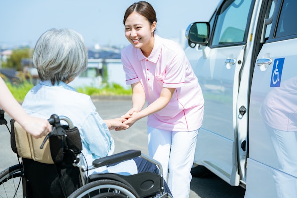 送迎の介護士と車いすに乗った高齢者